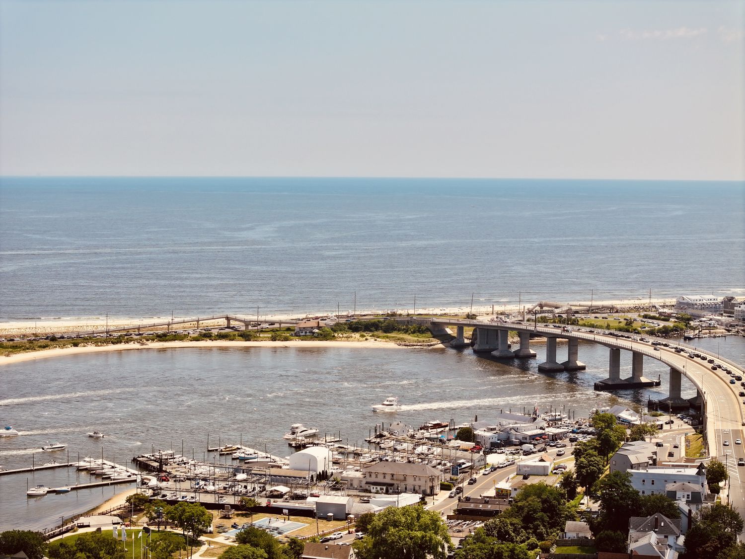 Aerial photograph of the Route 36 bridge crossing the water from the Highlands to Sea Bright, the town and marinas at its foot and the ocean beyond, 2026