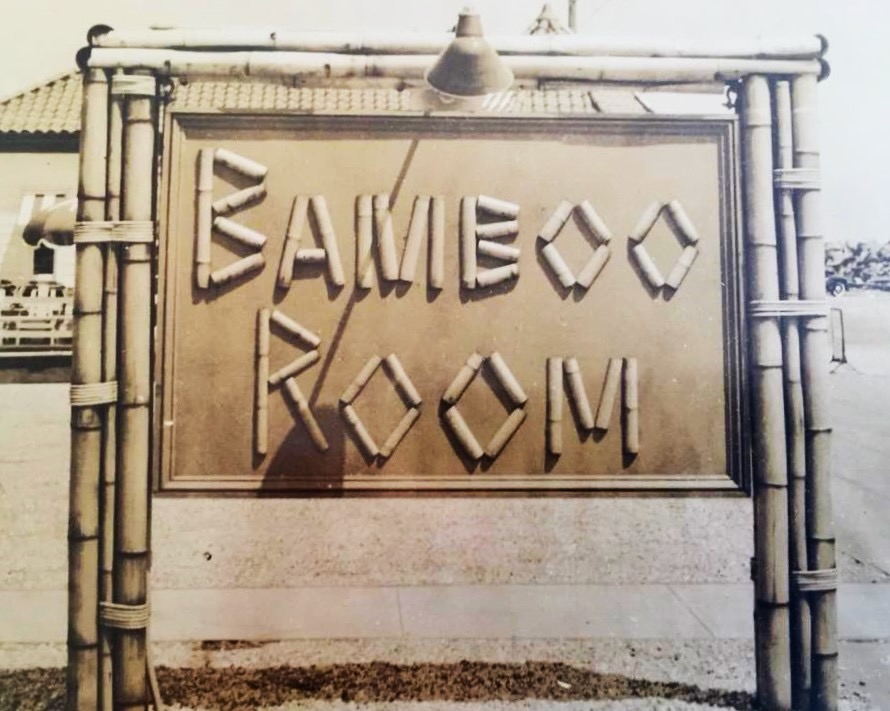 A sepia-toned photograph of the Bamboo Room's exterior sign at Highland Beach, ca. 1930s — the letters BAMBOO ROOM cut from bamboo pieces, framed in bamboo poles, with the stucco building behind
