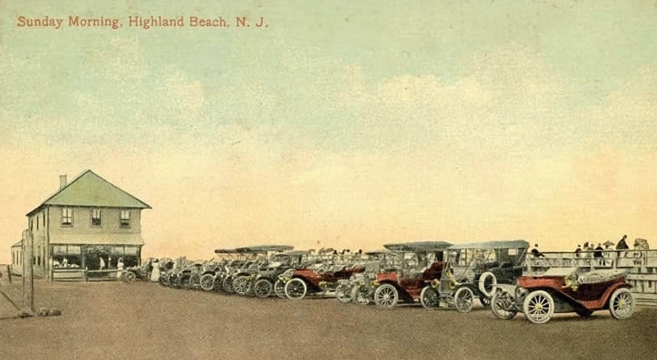 A hand-colored postcard ca. 1912 titled SUNDAY MORNING, HIGHLAND BEACH, N.J. — a long line of early touring cars parked outside a small clapboard bath-house office at the beach entrance