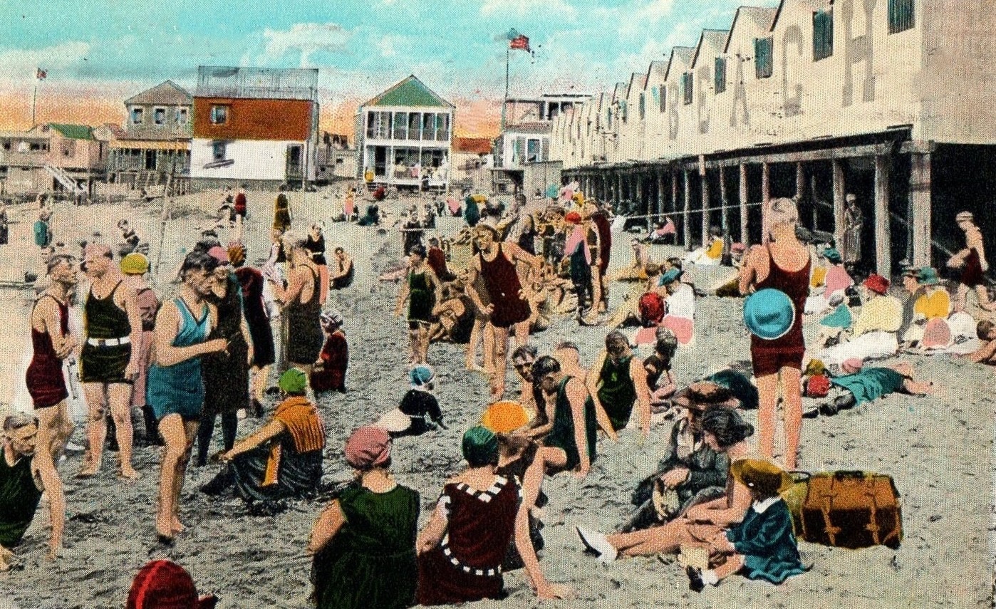 A hand-colored postcard ca. 1922 of Highland Beach at bathing hour — dozens of bathers in twenties bathing costume on the sand, the HIGHLAND BEACH bathhouse row on wooden pilings at right, the cottage colony at left